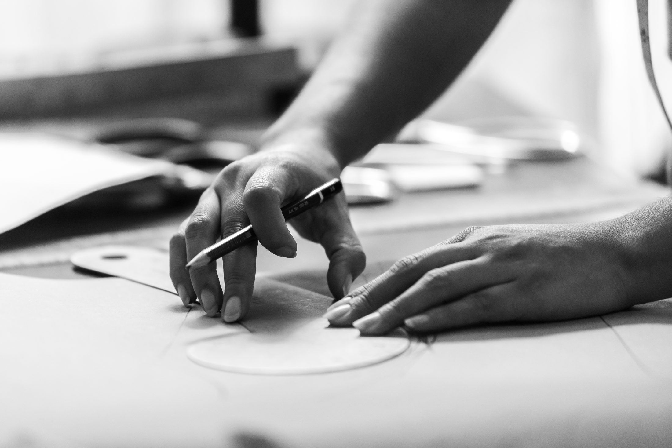 Hands drafting a pattern in monochrome to express the atelier discipline behind made-to-measure
