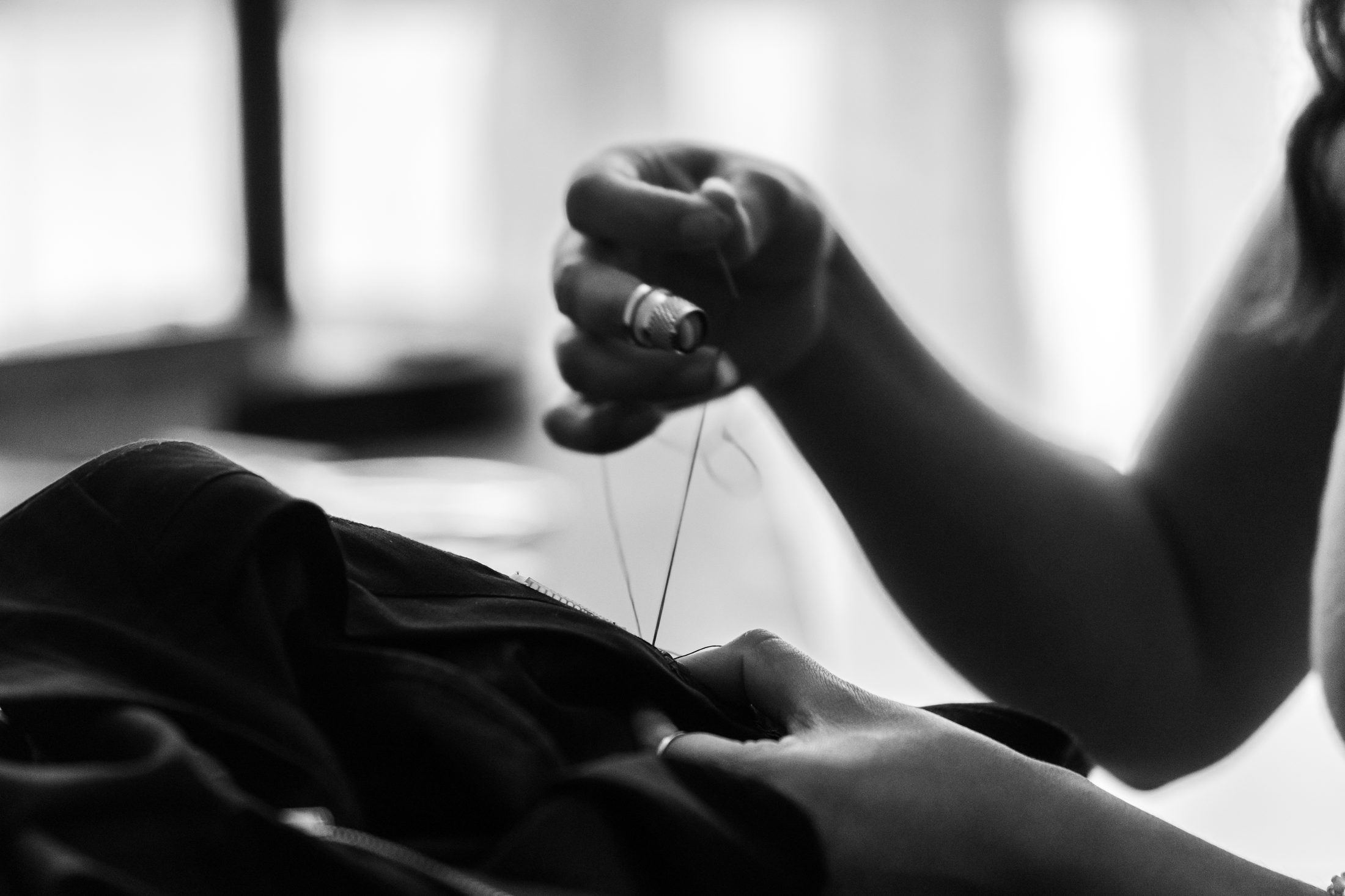 Hands stitching cloth in monochrome to suggest the preparation behind each appointment