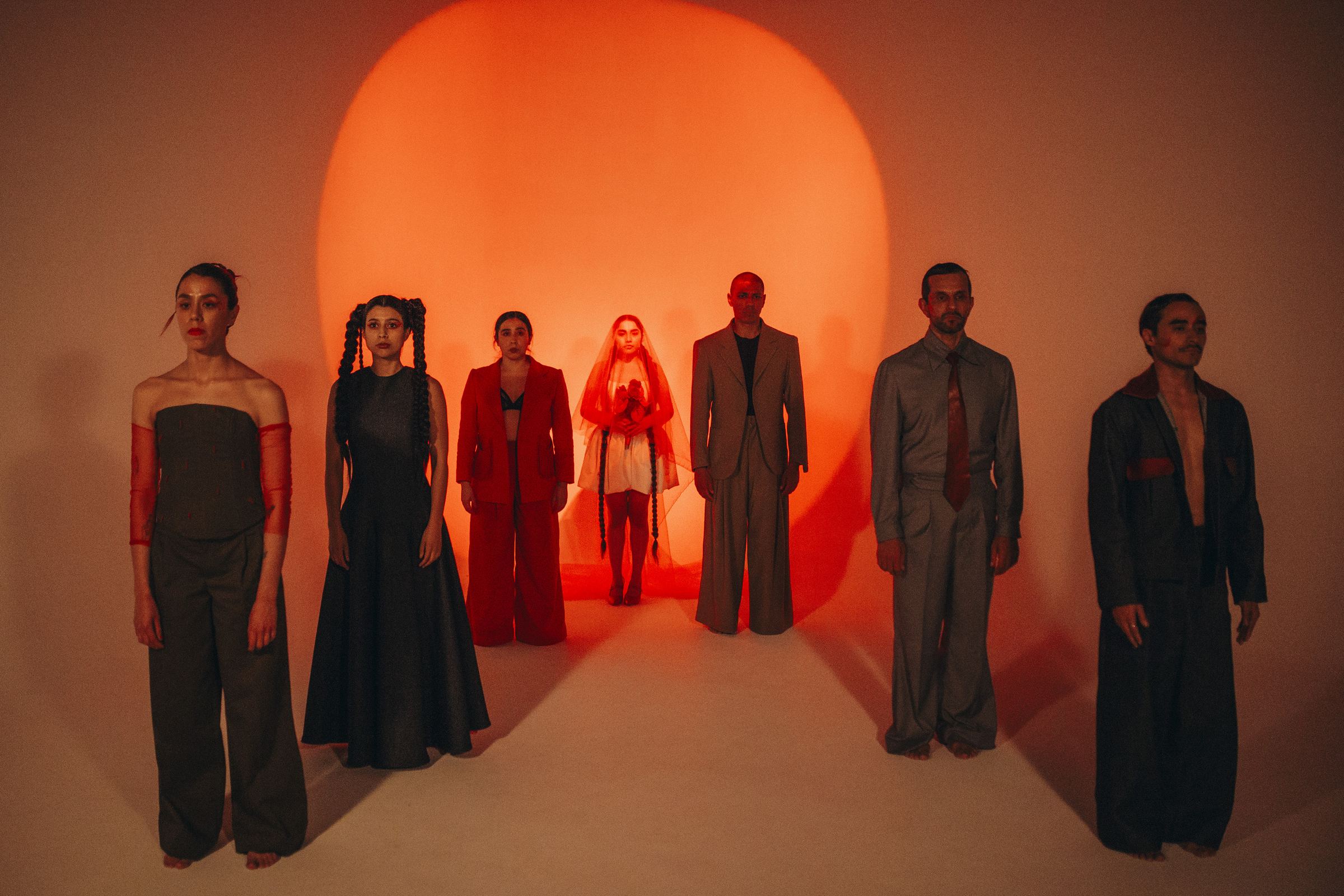 Editorial group portrait staged against a glowing circular light in warm red tones